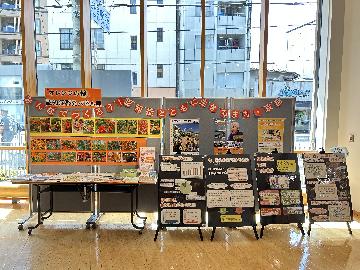 パネルにオレンジ色の花等の写真が貼られている。認知症関連のパンフレットやチラシが机にが並べられている。