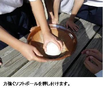もみすりの様子2：力強くソフトボールを押し付けます。