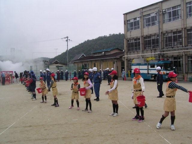 地域住民や地元消防団とともに消火バケツリレーを実施するクラブ員1