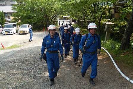背負い式水のうに水を満たし，現場に向かう第3てい団