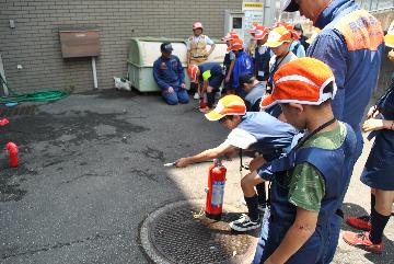 訓練用消火器で狙いを定めるジュニア消防団員