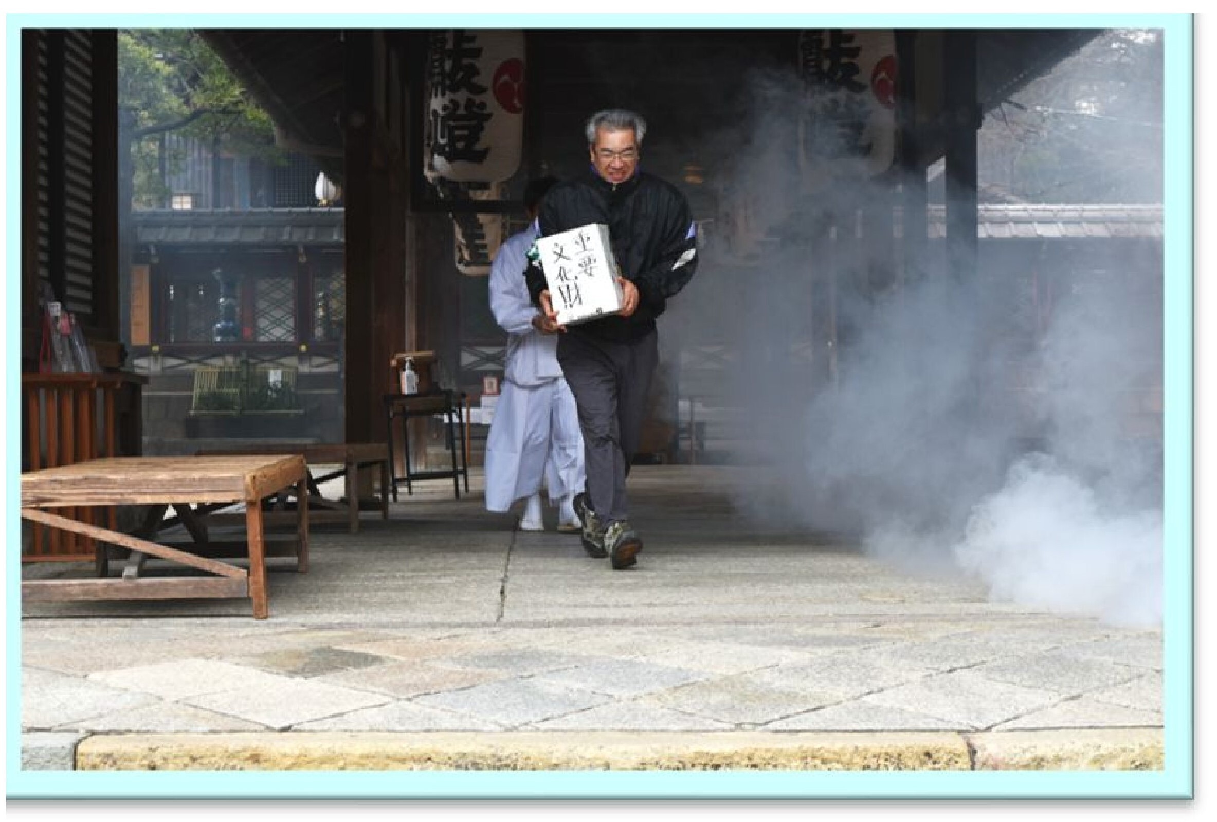 煙の中から重要物品を搬出する神社職員