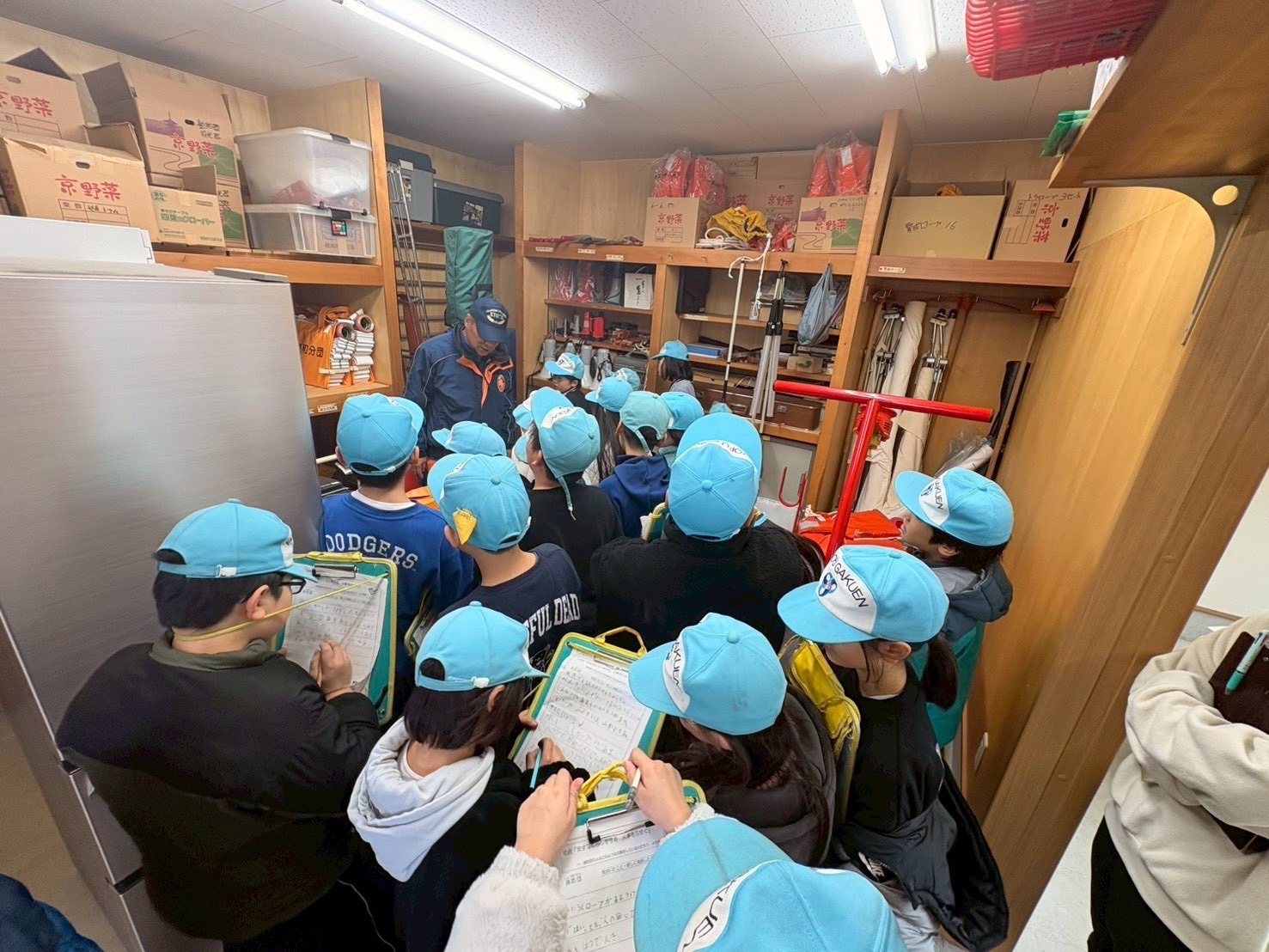 小学生が消防団器具庫で資器材の説明を受けている様子。