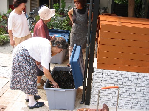 生ゴミを堆肥化ボックスに入れる会員