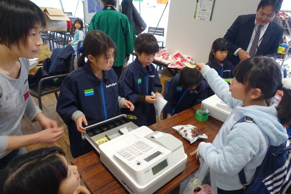 体験後の給料で商品を買う子どもとレジを打つ子ども